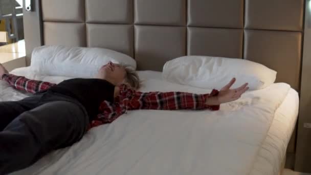 Счастливая женщина с пробежки падает на кровать в отеле после экскурсии. - Кадры, видео