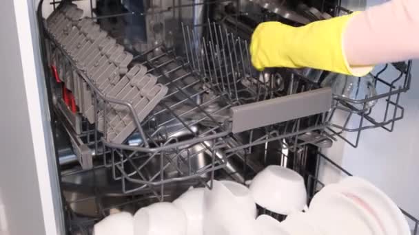 A womans hands load dirty dishes into a dishwasher, an open door reveals a built-in dishwasher, and dishes are loaded with dishwashing capsules.  - Záběry, video