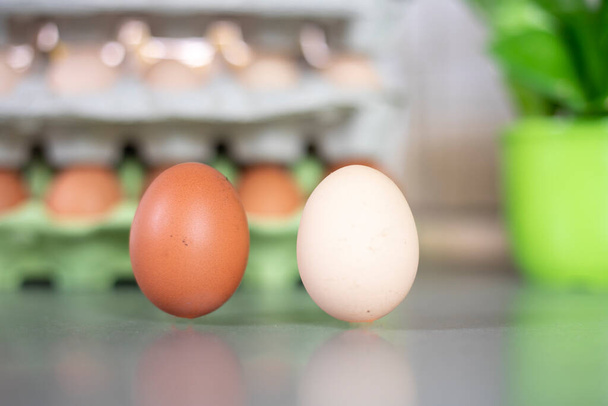 zbliżenie dwóch jaj w pobliżu pojemnika z jajkami. Kryzys gospodarczy - Zdjęcie, obraz