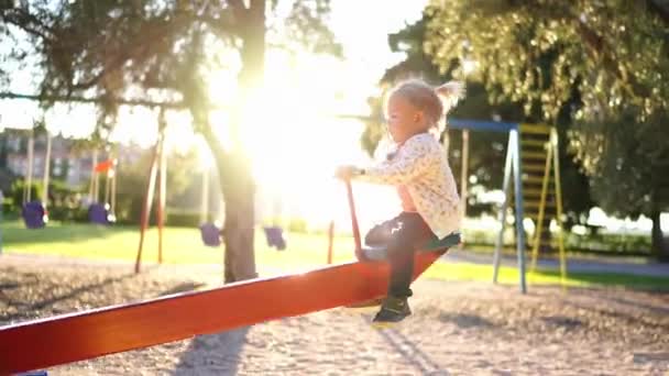 La bambina oscilla su un bilanciere oscillante nel parco giochi. Filmati 4k di alta qualità - Filmati, video