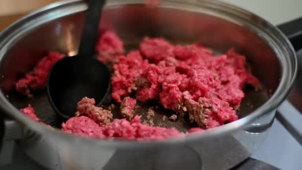 Процесс приготовления начинается с брызг масла на сырую говядину в горячей сковороде. - Кадры, видео