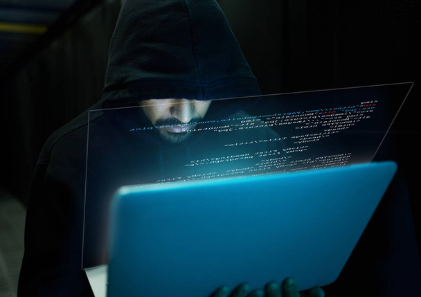 Cyber security, crime and hacker with laptop typing in data center, stealing sensitive digital information and coding. Technology, software and man hacking in database to update ransomware on website. - Photo, image