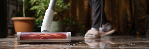 Акумуляторний пилосос з турбо пензлем очищає плитку у вітальні. Сучасна концепція технології прибирання будинку
 - Фото, зображення