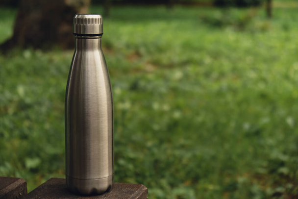 Water bottle. Reusable steel thermo water bottle on green grass. Sustainable lifestyle. Plastic free zero waste free living. Go green Environment protection. Health-conscious. Steel thermo water bottle of silver, on background of blurred grass.  - Foto, imagen