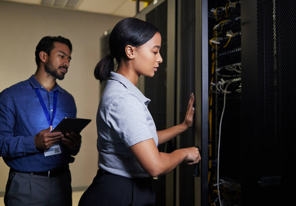 Server room, engineer teamwork and woman opening panel for maintenance or repairs at night. Cybersecurity, programmers and female with man holding tablet for software or networking in data center - Fotografie, Obrázek