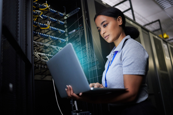 Laptop, netwerk en datacenter met een zwarte vrouw het ondersteunen ingenieur werken in een donkere serverruimte. Computer, cybersecurity en analytics met een vrouwelijke programmeur probleemoplossing of probleemoplossing. - Foto, afbeelding