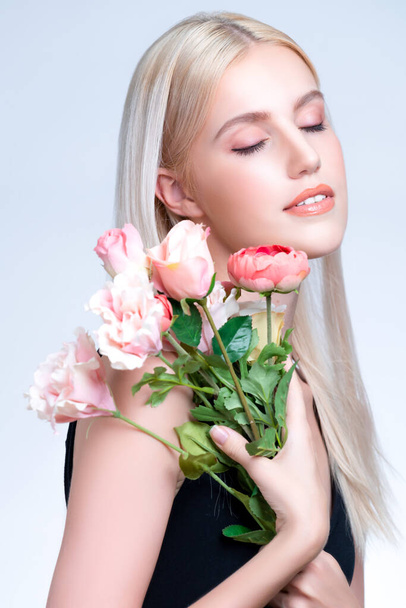 Closeup young personable woman with natural makeup and healthy soft skin holding rose for beauty care advertising in isolated background. Beautiful pretty model girl with flower concept. - Photo, image
