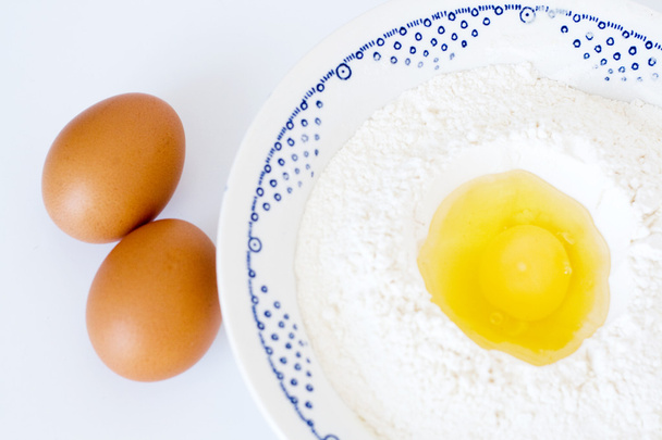 Plate with flour, eggs lying on a white background - Foto, Imagem