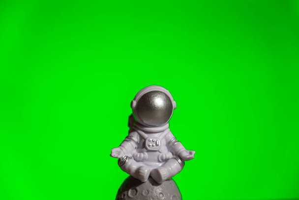Πλαστικός αστροναύτης παιχνιδιών σε πράσινο χρώμα βασικό φόντο πρότυπο Mock up Copy space. Έννοια της εκτός γης ταξίδια, ιδιωτικές διαστημικές εμπορικές πτήσεις. Διαστημικές αποστολές και βιωσιμότητα - Φωτογραφία, εικόνα