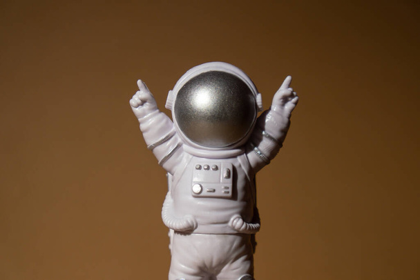 Plastic toy figure astronaut on beige neutral background Copy space. Concept of out of earth travel, private spaceman commercial flights. Space missions and Sustainability - Fotó, kép