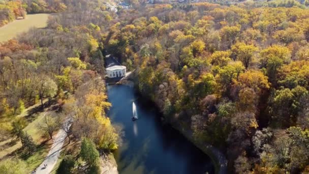 Schöner Panorama-Herbst-Landschaftspark, viele Bäume mit gelben Blättern, See mit Brunnen in der Mitte, Architektur, große Steine, Wege, Menschen, die an sonnigen Herbsttagen spazieren gehen. Drohnen aus der Luft - Filmmaterial, Video
