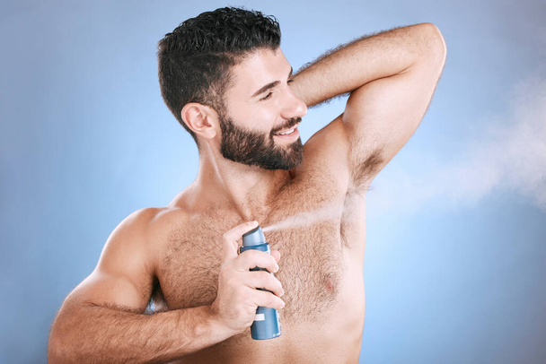 Deodorant, spray and man in studio for hygiene, fresh scent or underarm perfume. Male model spraying armpit for body odor, smell and cleaning cosmetics, shower product and skincare mist on background. - Photo, Image