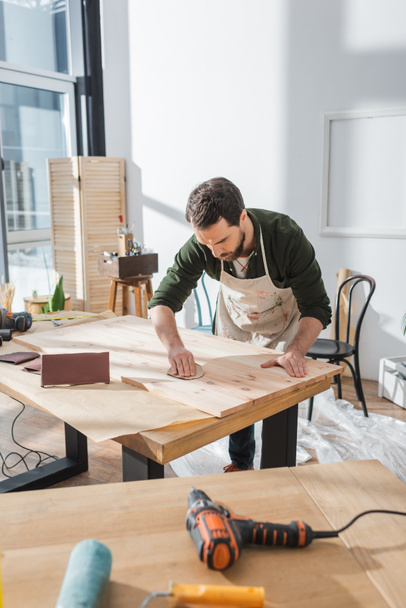 Craftsman using sandpaper on wooden board in workshop  - Fotografie, Obrázek