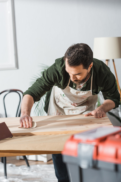 Craftsman in dirty apron sanding wooden board  - Fotoğraf, Görsel