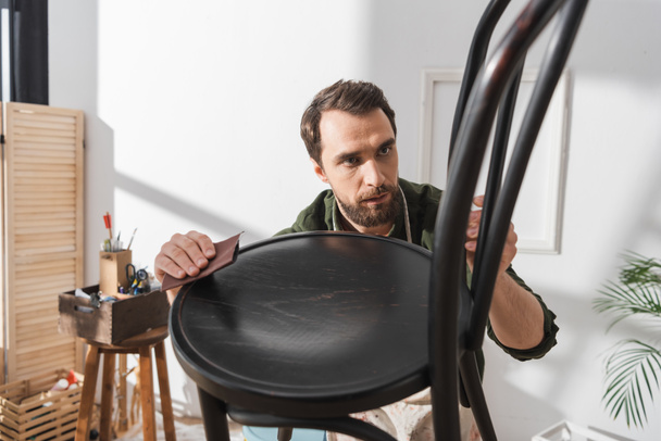 Орієнтований реставратор шліфування дерев'яного стільця в майстерні
  - Фото, зображення