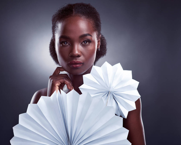 Elegant beauty. Studio portrait of a beautiful young woman posing with origami fans against a black background - Foto, Bild