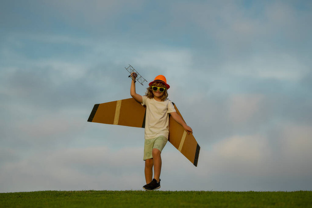 The concept of child kindness and childhood. Kid having fun with toy airplane in field. Child pilot aviator with airplane dreams of traveling in summer in nature - Foto, Imagen