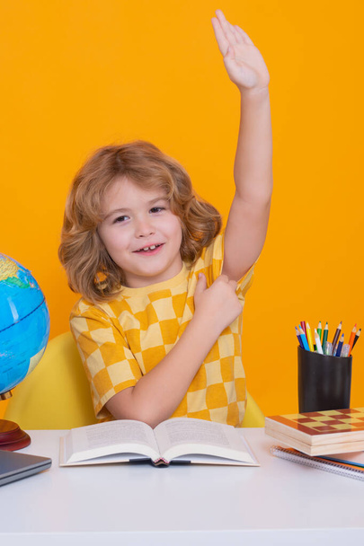 School child raising hands, willing to answer question. School child student learning in class, study english language at school. Elementary school child. Portrait of funny pupil learning - Photo, Image