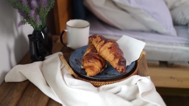breakfast, cozy, morning, holidays and winter concept - cozy bedroom with cup of coffee and croissant on wooden board in bed at home - Video, Çekim
