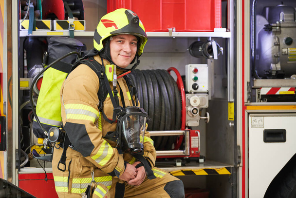 Portrait of firefighter at work in protection wear in front fire-engine - Foto, Imagen