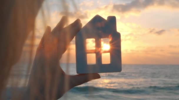 Closeup anonymous female admiring sunset sky through window of toy house on beach near waving ocean - Filmmaterial, Video