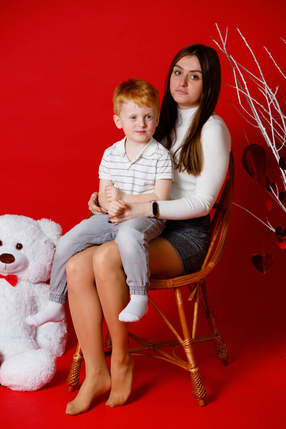 14.02.23. Vinnytsia, Ukraine: Portrait of a brother and sister on a red background at home. Mother's Day is coming soon. Emotions and gifts from children - Valokuva, kuva