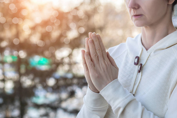 Woman praying on a blurred background raising her hands. - Zdjęcie, obraz