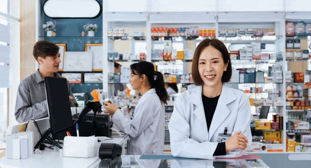 Portret zamożnego aptekarza azjatyckiego i wykwalifikowanego farmaceuty, butelka z lekami na półce w tle w aptece. Koncepcja farmaceuty pracującego nad kasjerem rozmawiającego z klientem w aptece. - Zdjęcie, obraz