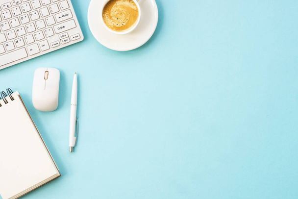Escritorio de mesa de oficina con laptop, bloc de notas, bolígrafo y taza de café. Piso puesto en azul con espacio de copia. - Foto, imagen