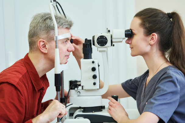 female optometrist optician doctor examines eyesight of male patient in eye ophthalmological clinic. BeH3althy - Fotografie, Obrázek