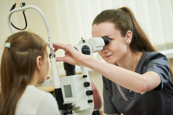 ophthalmology. female doctor optometrist checks eye sight of young girl. BeH3althy - 写真・画像