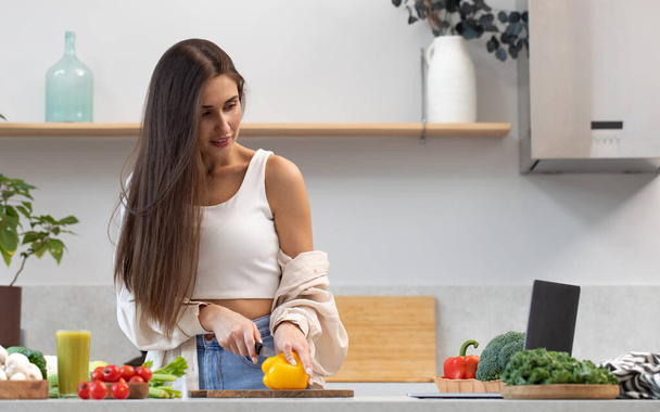 An attractive woman is watching a cooking class on cooking a vegetarian dish. Video recipe, healthy food concept. - Foto, Imagen