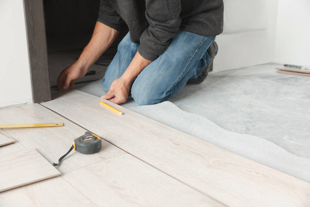 Worker installing new laminate flooring in room, closeup - Photo, Image