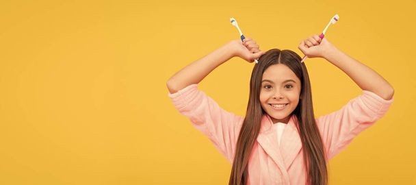 Kindergeluk. Morgen routine. Het kind draagt een zacht nachtpak. Banner van kind meisje met tandenborstel, studio portret, header met kopieerruimte - Foto, afbeelding