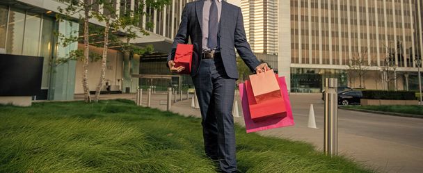 beschnitten Geschäftsmann im Anzug halten Pakete und Geschenkbox zu Fuß aus dem Büro, Frauentag. - Foto, Bild