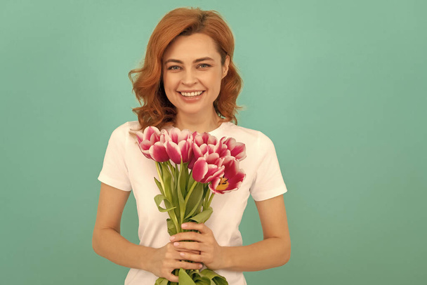 смеющаяся женщина с цветочным букетом тюльпана на синем фоне. - Фото, изображение