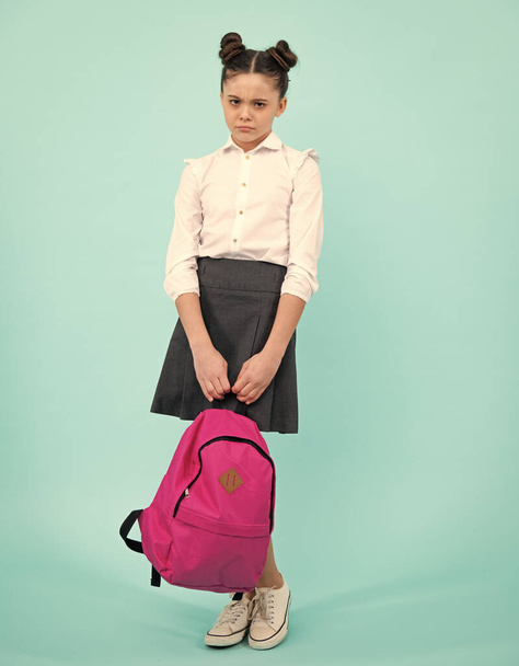 Unhappy sad teenager school girl. Schoolgirl in school uniform with school bag. Teenage girl student on blue isolated background. Learning knowledge and children education concept - Foto, imagen
