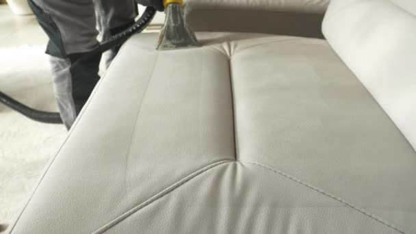 Глубокая очистка белой мягкой поверхности мебели с помощью вакуумной чистки. Выявление чистой ткани при тщательной стирке и пылесосе дивана в качестве обязательной домашней работы во время весенней уборки - Кадры, видео