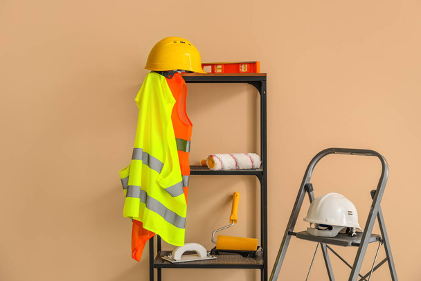Stepladder and shelving unit with builder's equipment near beige wall - Foto, Imagen