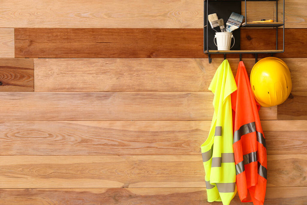 Полка со строительными материалами и светоотражающими жилетами на деревянной стене - Фото, изображение