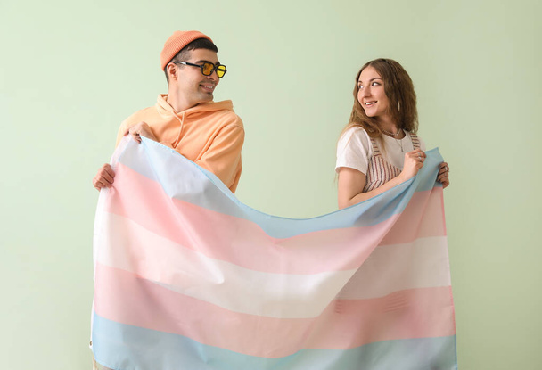 Νεαρό ζευγάρι με σημαία τρανσέξουαλ σε πράσινο φόντο - Φωτογραφία, εικόνα