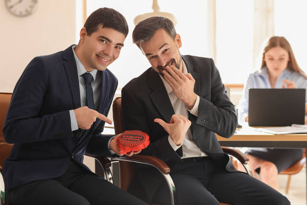 Des jeunes hommes avec un coussin qui rient au bureau. Avril Fête des fous - Photo, image