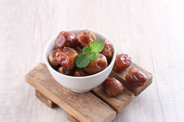 dates in a bowl on a wooden background - Photo, Image