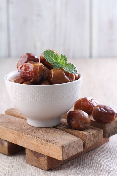 dates in a bowl on a wooden background - Photo, Image