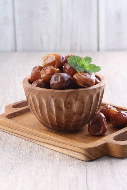 dried dates in a wooden bowl on a table - Photo, Image