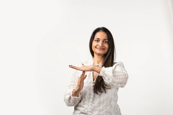 Indian mid age serious woman showing a time out gesture with hands, isolated white background - Foto, Imagen