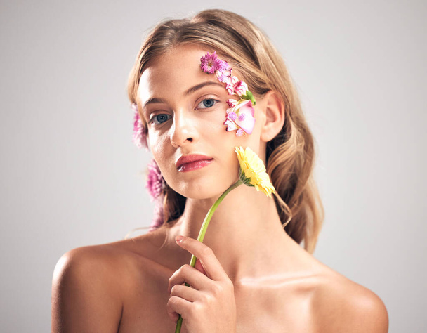Beauty, flower and portrait of woman in studio with a skincare, natural and face routine. Floral, health and female model with organic, self care and fresh skin or facial treatment by gray background. - Fotó, kép