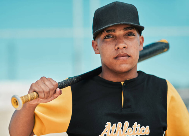 I think that baseball is by far the best sport. a young baseball player holding a baseball bat while posing outside on the pitch - Photo, Image