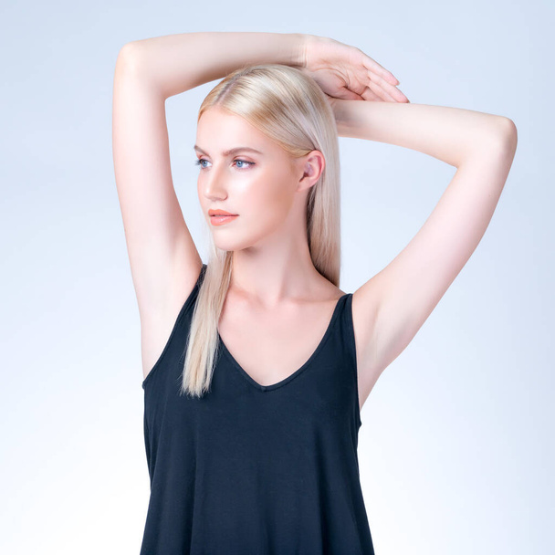 Personable woman lifting her armpit showing hairless hygiene underarm as beauty posing for cleanliness and perfect smooth skincare treatment in isolated background. Hair removal and epilation concept. - Photo, image