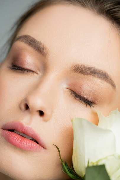 close up portrait of young woman with closed eyes near fresh rose - Foto, Imagem